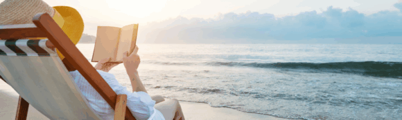 Person reading alone on a quiet beach, symbolizing summer reflection and self-care.