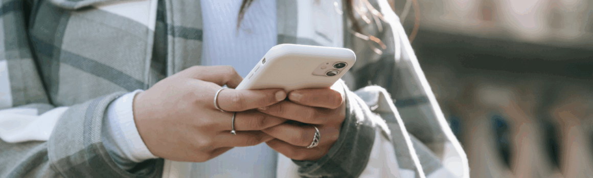 Close-up of a woman's hands holding an iPhone, displaying a blog titled 'Digital Wellness: Finding Balance in Our Always-Connected World' on the screen, emphasizing mindfulness in technology use.