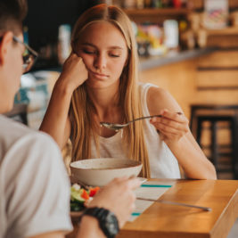 Adult woman with eating disorder looking down at bowl of soup