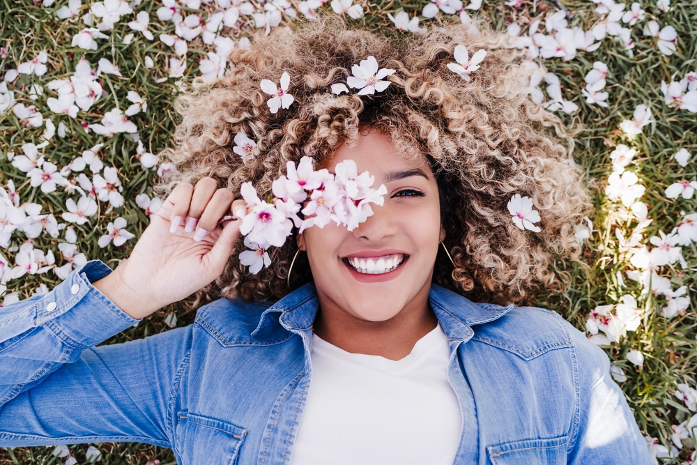 Woman laying down in field of flowers, practicing mindfulness for mental health